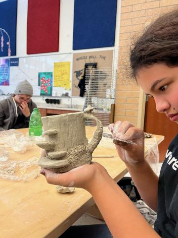 student working on clay mug
